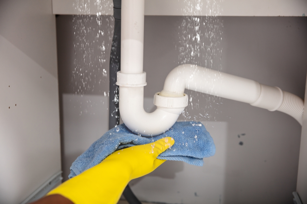 Addressing Leaks in Hot Water System Repair » Hot Water System hand in gloves holding a towel for catching leak on a hot water system